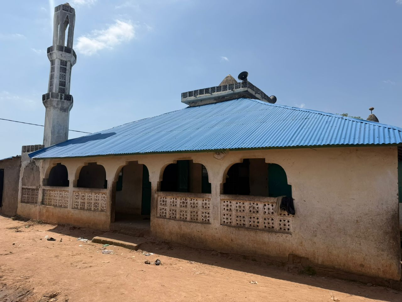The masjid of Madarasa Muhammad Rasulullah — a single-story building with a blue roof and a white minaret